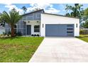 Modern home featuring a two-car garage, stylish gray and white facade, green lawn, and fresh landscaping at 19160 Ruskin Ave, Port Charlotte, FL 33954