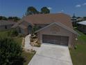 Inviting home featuring a lush lawn, landscaped front yard, and a spacious two-car garage at 23090 Ambassador Ave, Port Charlotte, FL 33954