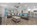 Open-concept living room with wood-look tile flooring, a sectional sofa, and views into the kitchen at 25308 Rupert Rd, Punta Gorda, FL 33983