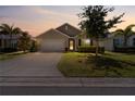 Charming one-story home with a well-manicured lawn, a two-car garage, and lush landscaping at dusk at 25312 E Lenox Cir, Punta Gorda, FL 33950