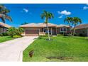 Charming one-story home boasts a lush green lawn, mature palm trees, and a paved driveway leading to a two-car garage at 695 Macedonia Dr, Punta Gorda, FL 33950