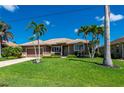 Inviting single-story home features a well-kept lawn, mature landscaping, and a two-car garage for ample parking space at 695 Macedonia Dr, Punta Gorda, FL 33950