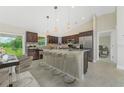 Modern kitchen with stainless steel appliances, a large island with bar seating, and tile backsplash at 7381 De Brita Rd, North Port, FL 34291