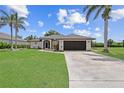 Lovely single-story home with a well-maintained lawn, a dark garage door and tropical palm trees at 7448 S Blue Sage, Punta Gorda, FL 33955