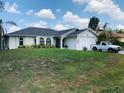 Charming home featuring a well-maintained lawn, attached garage, and lovely front yard landscaping at 1017 Guild St, Port Charlotte, FL 33952