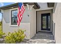 Close-up of the front entry featuring a decorative glass door, American flag, and meticulously maintained landscaping at 111 Britt Rd, Rotonda West, FL 33947