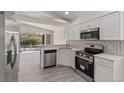 Modern kitchen featuring stainless steel appliances, white cabinets, and views of the pool area at 118 Naomi Pl, Rotonda West, FL 33947