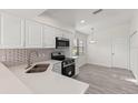 Well-lit kitchen with modern appliances, stylish backsplash, light countertop, and sleek gray flooring at 118 Naomi Pl, Rotonda West, FL 33947