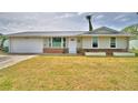 Charming one-story home with a metal roof, front planters, brick accents and an attached one-car garage at 13495 Newport Ave, Port Charlotte, FL 33981