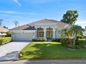 Well-maintained single-story home featuring a lush lawn, palm trees and a two-car garage at 13783 Palmetto Point Ct, Port Charlotte, FL 33953
