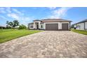 An exterior daytime view of a well-maintained single-story home with a three-car garage and brick driveway at 15 Tournament Rd, Rotonda West, FL 33947