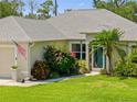 Well-maintained single-story home with a lush green lawn, inviting entrance, and mature landscaping at 17396 Cox Ave, Port Charlotte, FL 33948