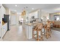 Modern kitchen with white cabinetry, granite countertops, island seating and an adjacent living space at 17629 Palmetto Pass Ln, Punta Gorda, FL 33982