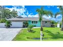 Charming single-story home featuring stone accents, a paved driveway, and lush landscaping with palm trees at 192 Danforth S Dr, Port Charlotte, FL 33980