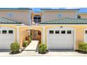 Charming condo with covered entrance, white garage door, and balcony above with chairs at 206 Gondola Park Dr # 206, Venice, FL 34292
