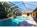 Beautiful screened-in pool area featuring a waterfall, lush plants, and an adjacent spa for ultimate relaxation at 25538 Rampart Blvd, Punta Gorda, FL 33983