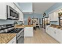 Open kitchen featuring white cabinets, stainless steel appliances, and a view into the dining area at 3225 Magnolia Way, Punta Gorda, FL 33950