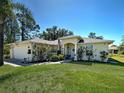 Beautiful one-story home featuring a well-kept lawn, mature landscaping, and attached garage at 4092 Troost St, North Port, FL 34288