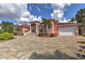 Beautiful light pink home featuring a two-car garage, manicured landscaping, and a paver driveway at 4409 Crews Ct, Port Charlotte, FL 33952