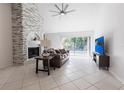 Bright living room with a stone fireplace, tile flooring, ceiling fan and sliding glass doors at 10289 60Th N Cir, Pinellas Park, FL 33782