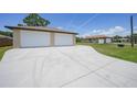 Detached three-car garage with a long concrete driveway and lush green lawn at 1039 Marlene St, Port Charlotte, FL 33952