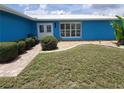 Close-up of a home's entrance with a paved walkway, vibrant blue exterior, and neatly trimmed hedges at 190 Casa Ln, Punta Gorda, FL 33950