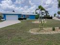 Inviting one-story home featuring a blue exterior, a well-kept lawn, and a neatly paved driveway at 190 Casa Ln, Punta Gorda, FL 33950