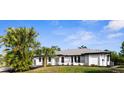 A charming, freshly painted home with a metal roof, black trim, and well-maintained landscaping at 19723 Midway Blvd, Port Charlotte, FL 33948