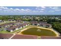 Community with a pond, lush green trees, well maintained landscaping, parking and multiple buildings from an aerial view at 25100 Sandhill Blvd # I-204, Punta Gorda, FL 33983