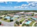 Aerial view of community including tennis courts, pool, shuffleboard, and clubhouse, surrounded by lush trees and landscaping at 25100 Sandhill Blvd # I-204, Punta Gorda, FL 33983