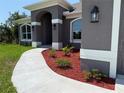 View of the covered front entrance of the home and manicured landscaping with fresh mulch at 13346 High Springs Ave, Port Charlotte, FL 33981