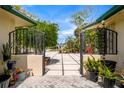 Wrought iron entry gate leading to home with lush tropical landscaping and expansive driveway at 155 Donna Ct, Punta Gorda, FL 33950