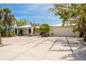 Charming single-story home featuring an expansive paved driveway and lush tropical landscaping at 155 Donna Ct, Punta Gorda, FL 33950