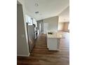 Modern kitchen with stainless steel appliances, white cabinets, an island with a sink, and sleek wood flooring at 16280 Minorca Dr, Punta Gorda, FL 33955