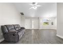 Cozy living room with gray tile floors, neutral walls, a ceiling fan, and a comfortable gray leather sofa at 19468 Edgewater Dr, Port Charlotte, FL 33948