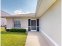 Inviting home entrance featuring a screened doorway, well-maintained lawn and lush flowering bushes at 26333 Nadir Rd # 111, Punta Gorda, FL 33983