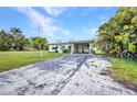 Exterior view of home featuring a long driveway with carport and tropical landscaping at 426 Burland St, Punta Gorda, FL 33950