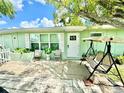 Exterior view of a well-kept home with a cozy front patio featuring outdoor seating and shaded by mature trees at 481 Reading Nw St, Port Charlotte, FL 33952