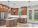 Modern kitchen featuring wood cabinets, stainless steel appliances, pendant lighting, and an island at 4862 Kiska Rd, North Port, FL 34288