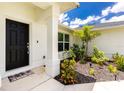 Close-up showcasing a classic black front door framed by white columns and lush landscaping at 5532 Veracruz Ter, Port Charlotte, FL 33981