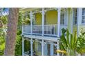 Charming yellow home with white trim, columns, a cozy balcony, and tropical landscaping at 936 Hemingway Cir, Tampa, FL 33602