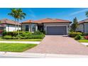 Beautiful single-story home with a red tile roof, a brick driveway, well-maintained landscaping, and a two-car garage at 1470 Hyssop Loop, North Port, FL 34289