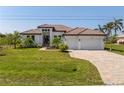 Stunning single-story home with a tile roof, three-car garage, and a meticulously landscaped front yard on a bright day at 15698 Meacham Cir, Port Charlotte, FL 33981