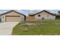 View of home with a detached garage with a chain link fence and grass at 22349 Columbus Ave, Port Charlotte, FL 33954