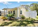 Side view of charming yellow cottage with a well-maintained, grassy yard and a white privacy fence at 233 N New York Ave, Englewood, FL 34223