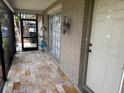 Covered entryway featuring a tiled floor, brick accent wall, and a charming vintage lantern at 8158 Trionfo Ave, North Port, FL 34287