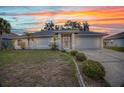 Well-maintained single-story home featuring a screened entry and attached two-car garage at sunset at 1210 Mccrory St, North Port, FL 34286