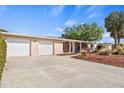 A single-story home featuring a spacious driveway, two-car garage, manicured lawn, and mature trees at 125 Small Se St, Port Charlotte, FL 33952