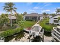 Backyard with a boat lift, dock, chairs, lush landscaping, and screened lanai at 1932 Los Alamos Dr, Punta Gorda, FL 33950