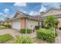 Well-maintained villa showing an attached garage, brick-paved driveway, lush shrubbery, and manicured garden at 2028 Lynx Run, North Port, FL 34288